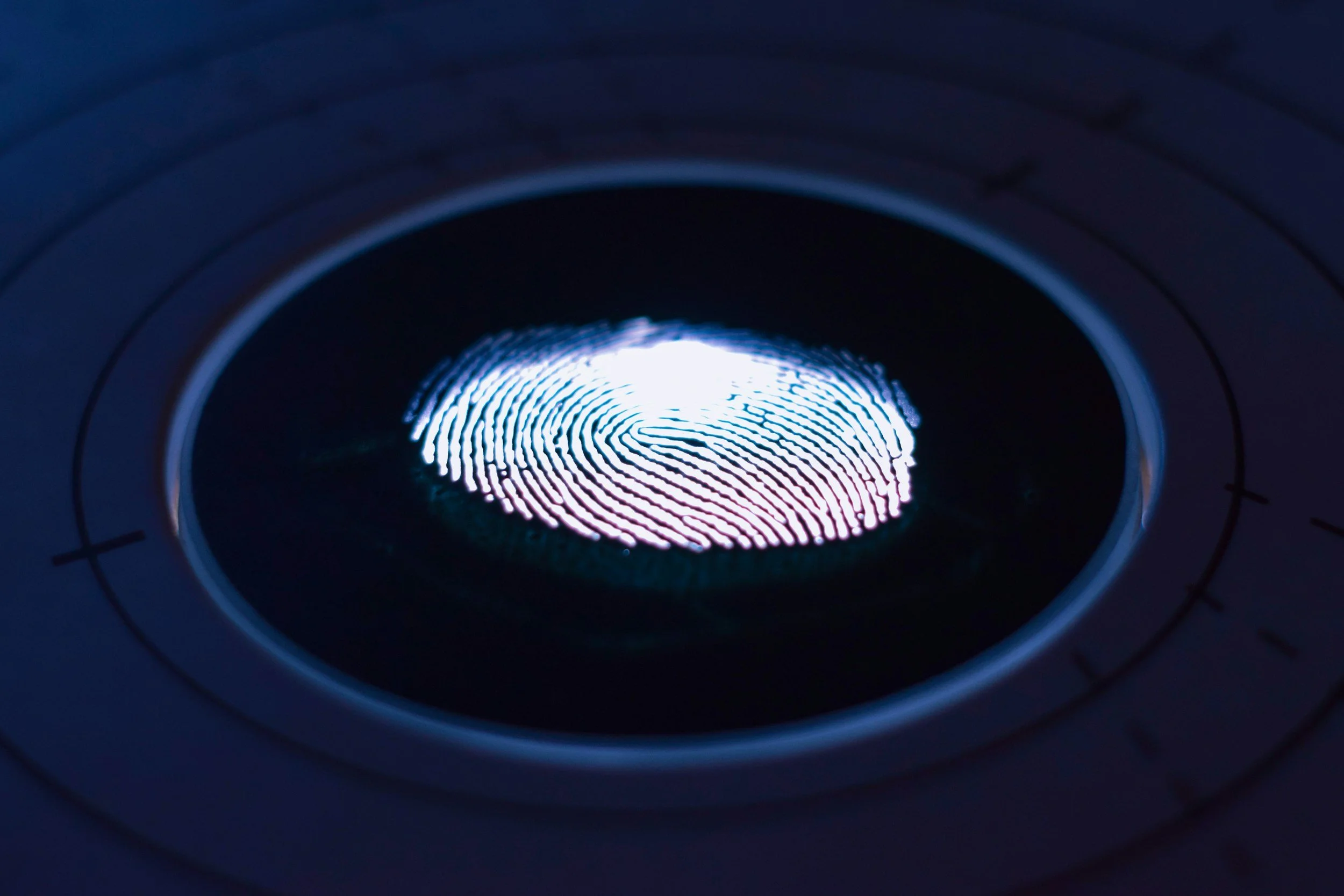 Close-up of a fingerprint illuminated by a bright light through a circular scanner, likely a fingerprint scanner on a device.